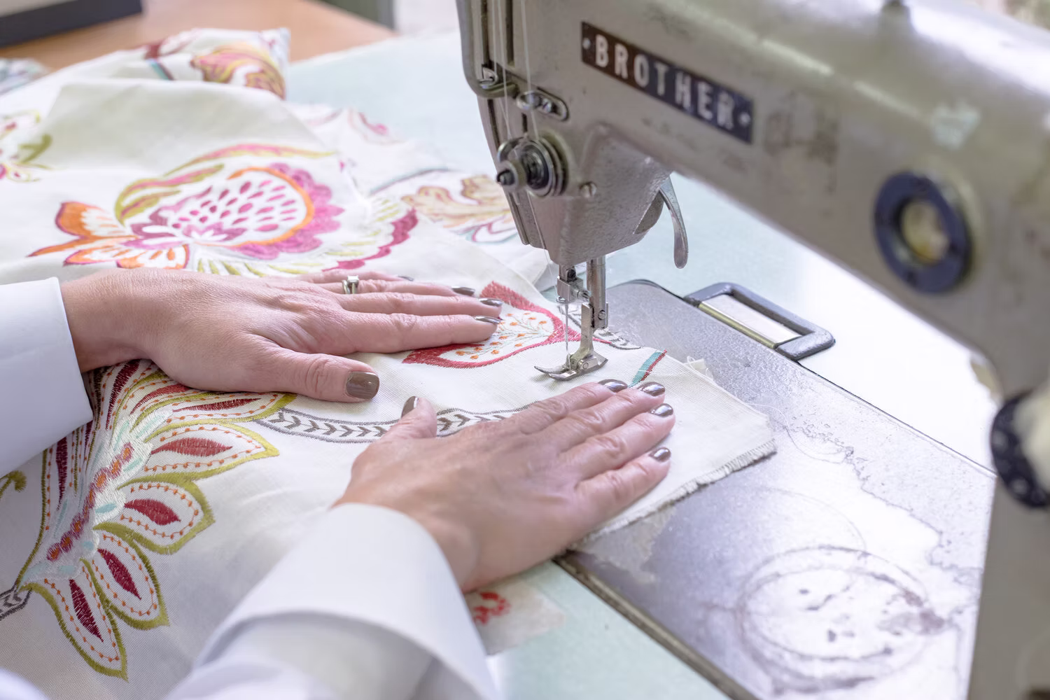 a maker sewing embroidered fabric on a machine in the Chatelaine workshop