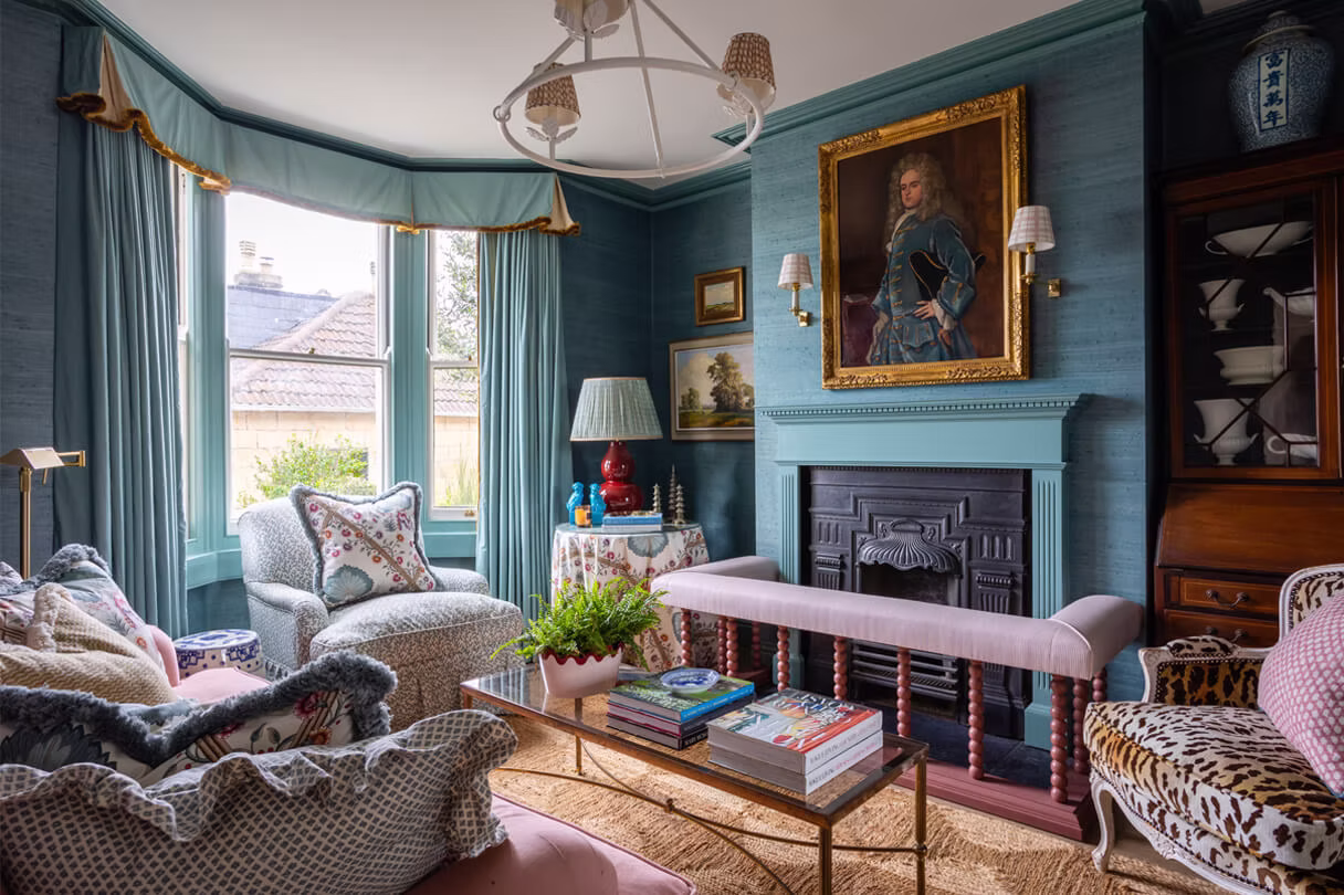 Maximalist living room layered with ruffled cushions, a leopard-print armchair and a mauve piped bench